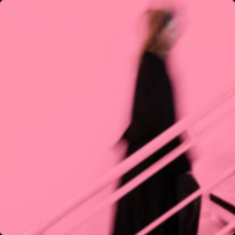 A blurred figure walking down stairs, washed in pink light