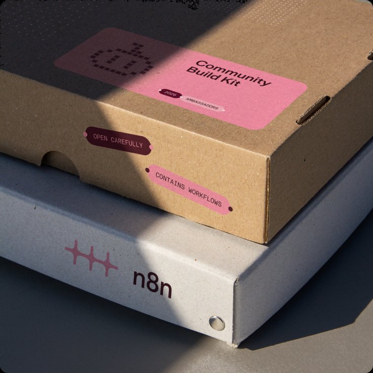 A cardboard “Community Build Kit” box with pink and deep pink stickers