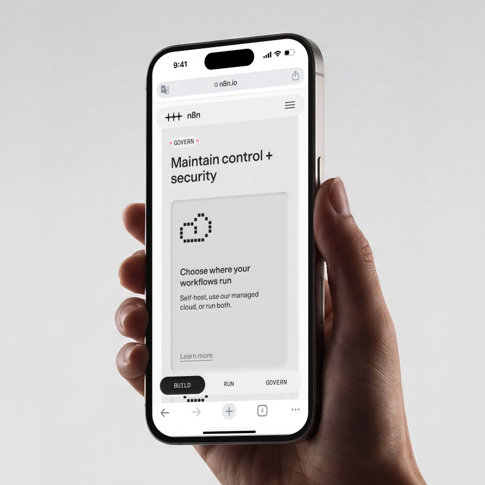 A hand holding a phone showing a debossed n8n interface