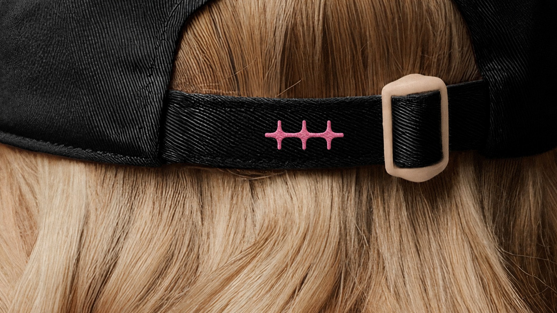 Pink n8n symbol embroidered on the strap of a black cap