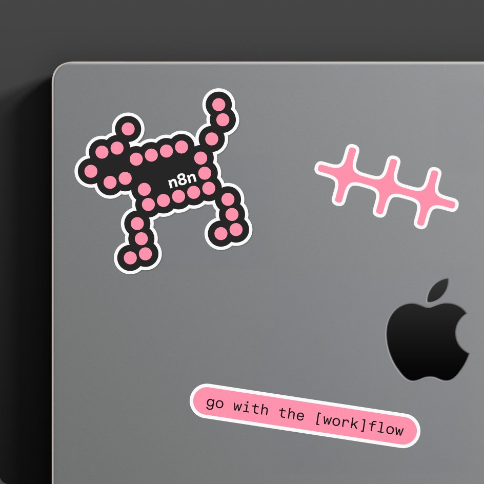Laptop lid with n8n stickers: a pixel node creature, the pink symbol, and “go with the [work]flow”